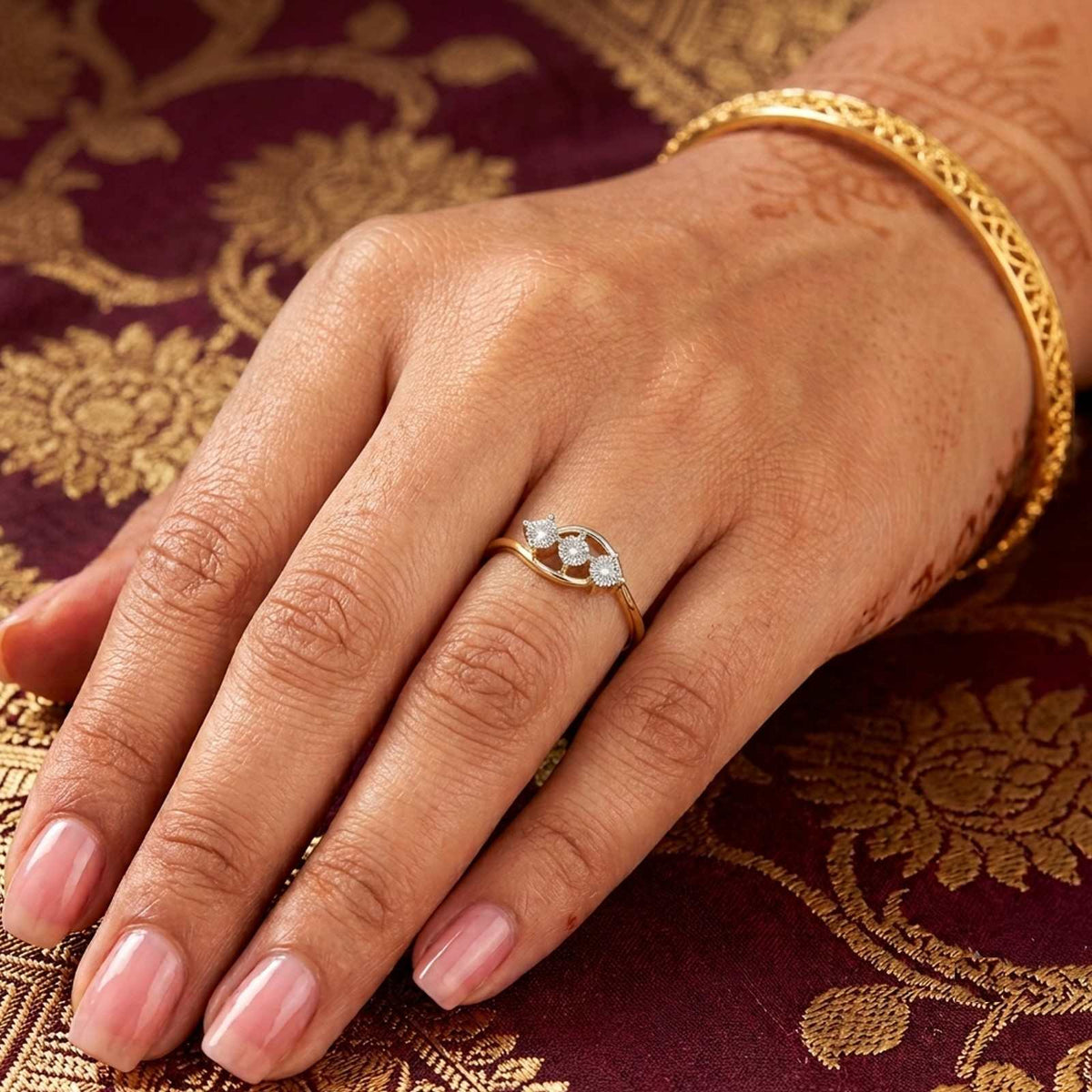 A gold ring with three clear diamond, resting on a person's finger.