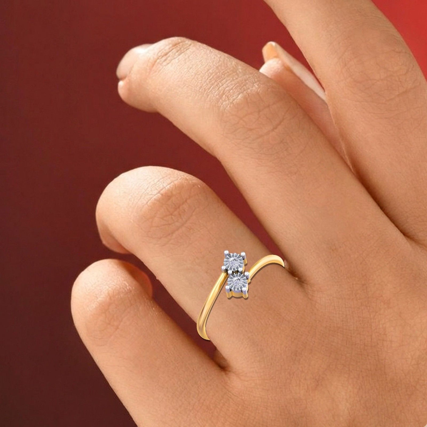 Gold and diamond women's ring on a hand against a red background