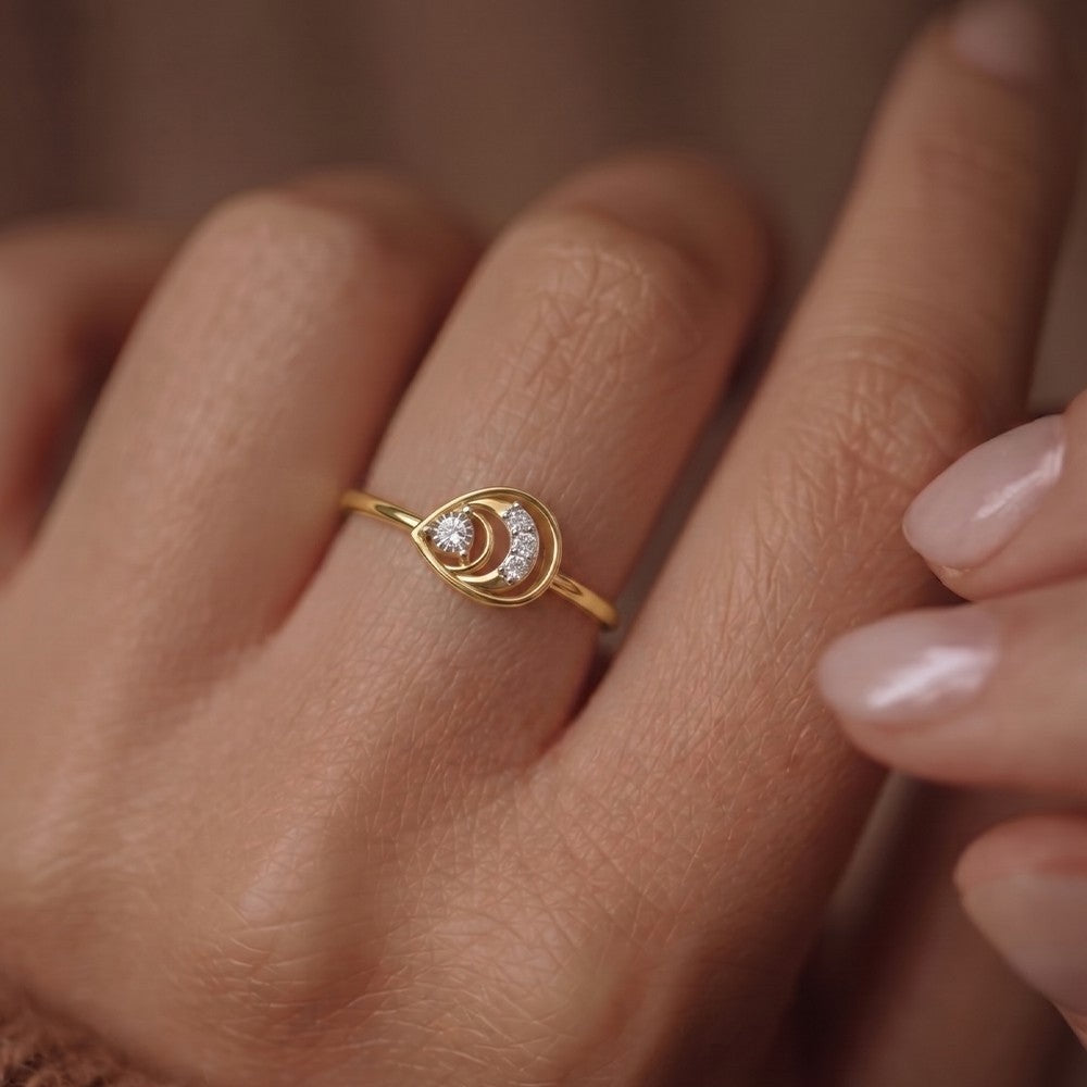 Gold ring with a diamond on a person's finger against a neutral background