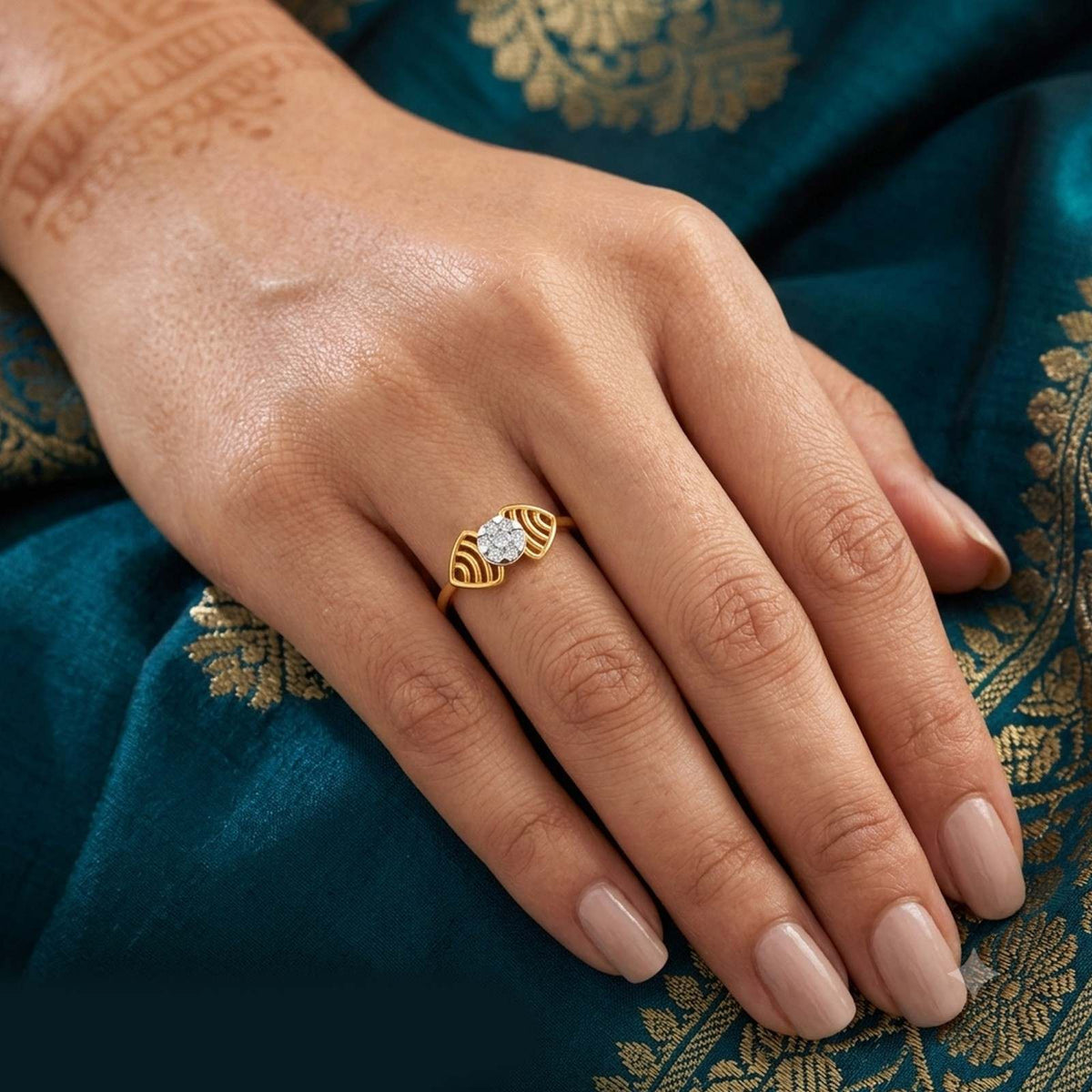 A gold ring with a round clear cluster, displayed on a person's finger.