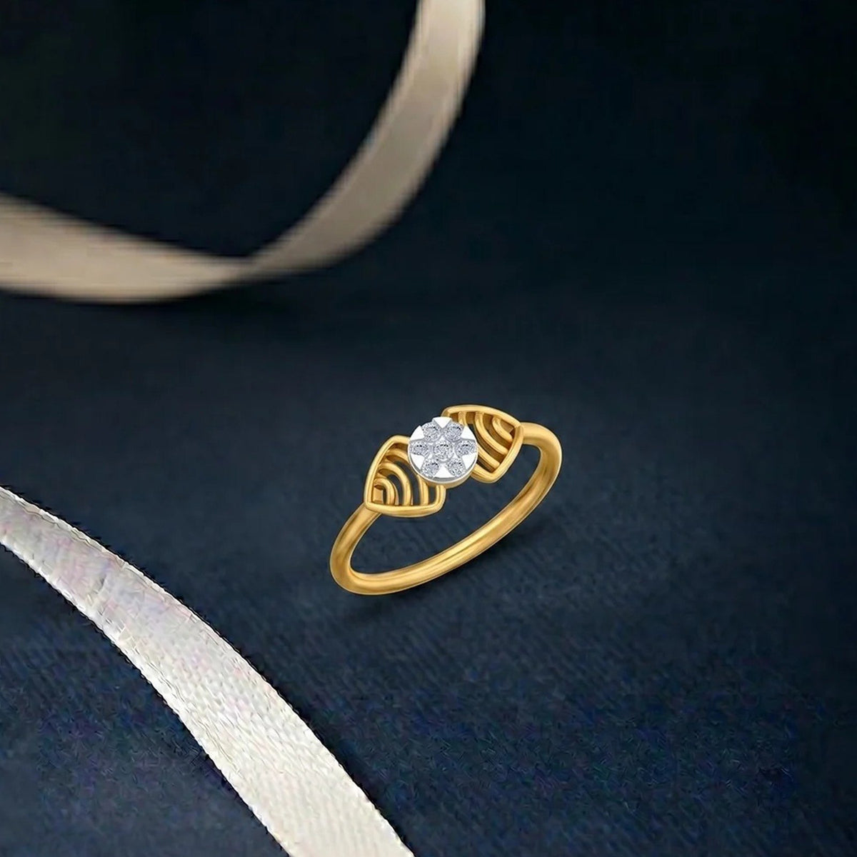 A gold ring with a round clear cluster, displayed on a dark navy textured surface with a white ribbon.