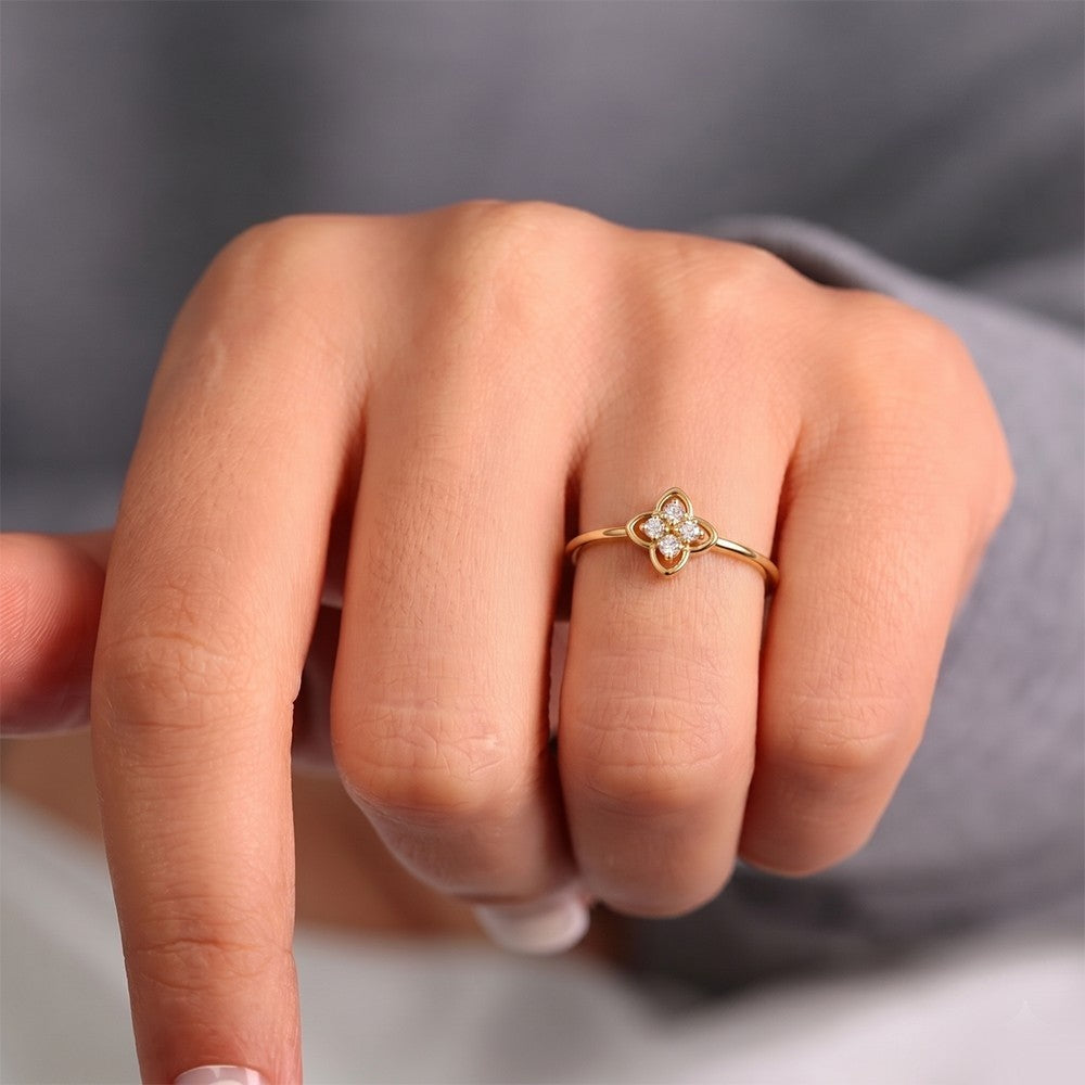 Gold ring with a diamond on a person's finger against a neutral background
