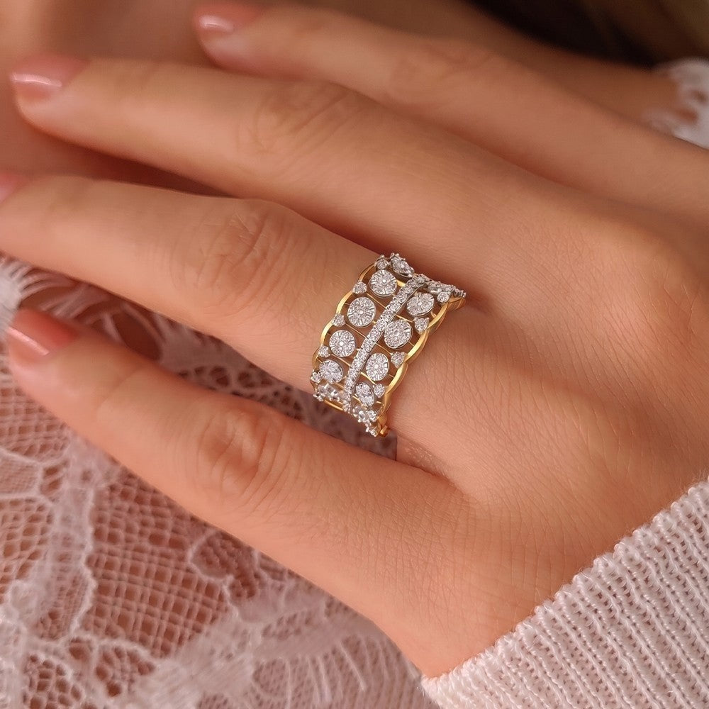 A gold ring with pavé-set clear stones worn on a hand, shown in a close-up lifestyle shot against a soft pink lace background.