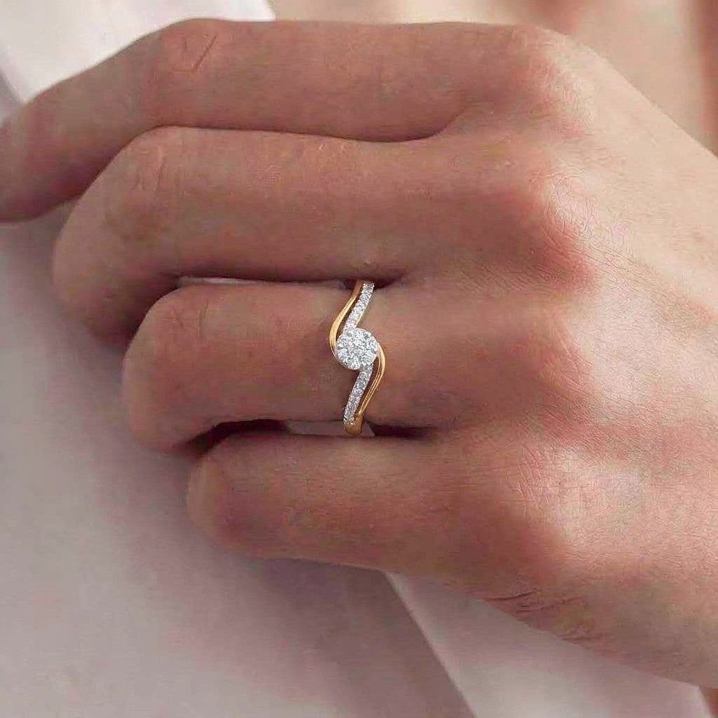 Gold ring with diamonds on a person's finger against a neutral background