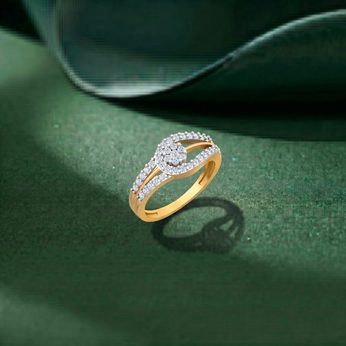 A gold ring with a floral-shaped diamond cluster, displayed on a textured dark green surface with a soft shadow.