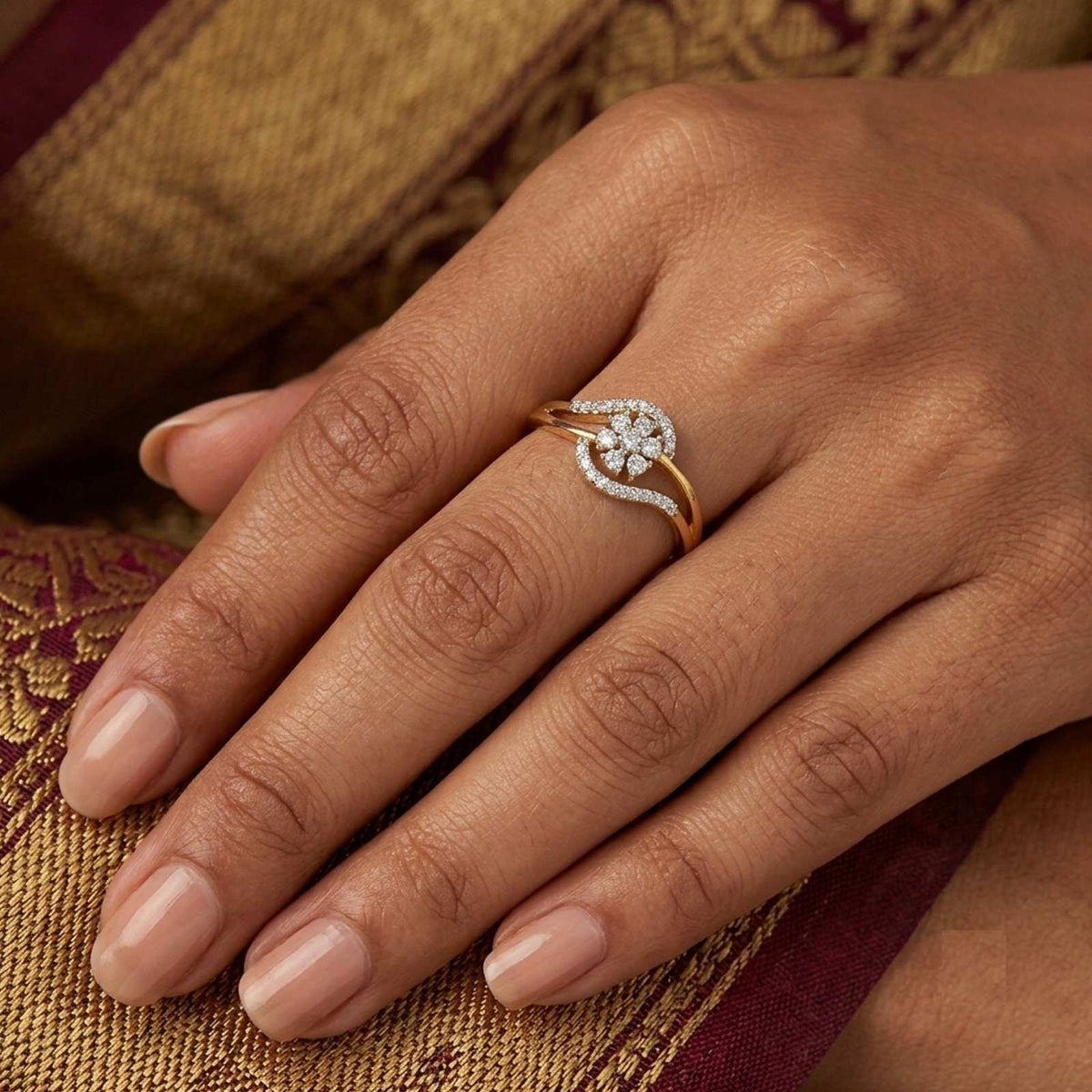 A gold ring with cluster ring setting worn on a woman's finger.