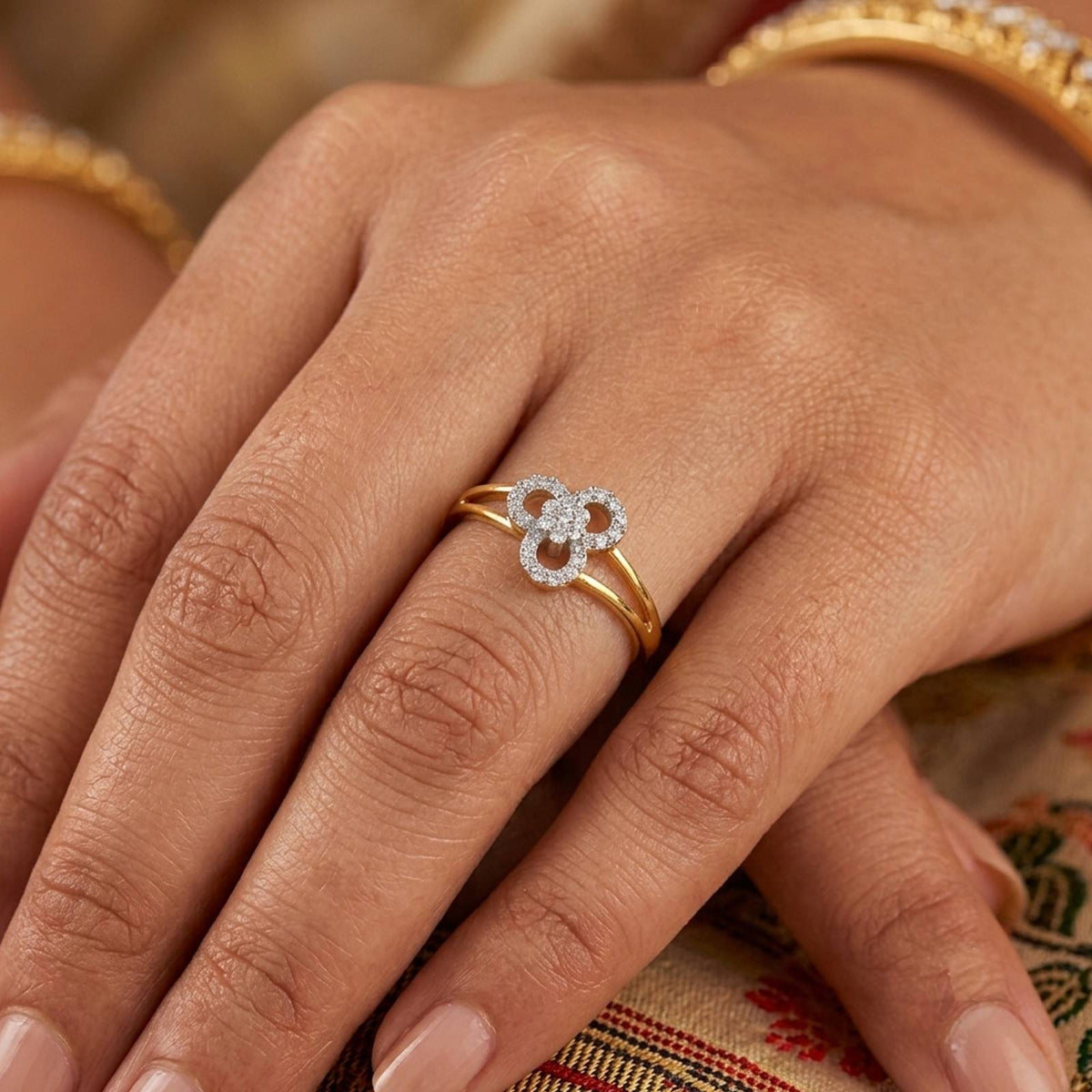 Gold and diamond with floral design on a person's finger.