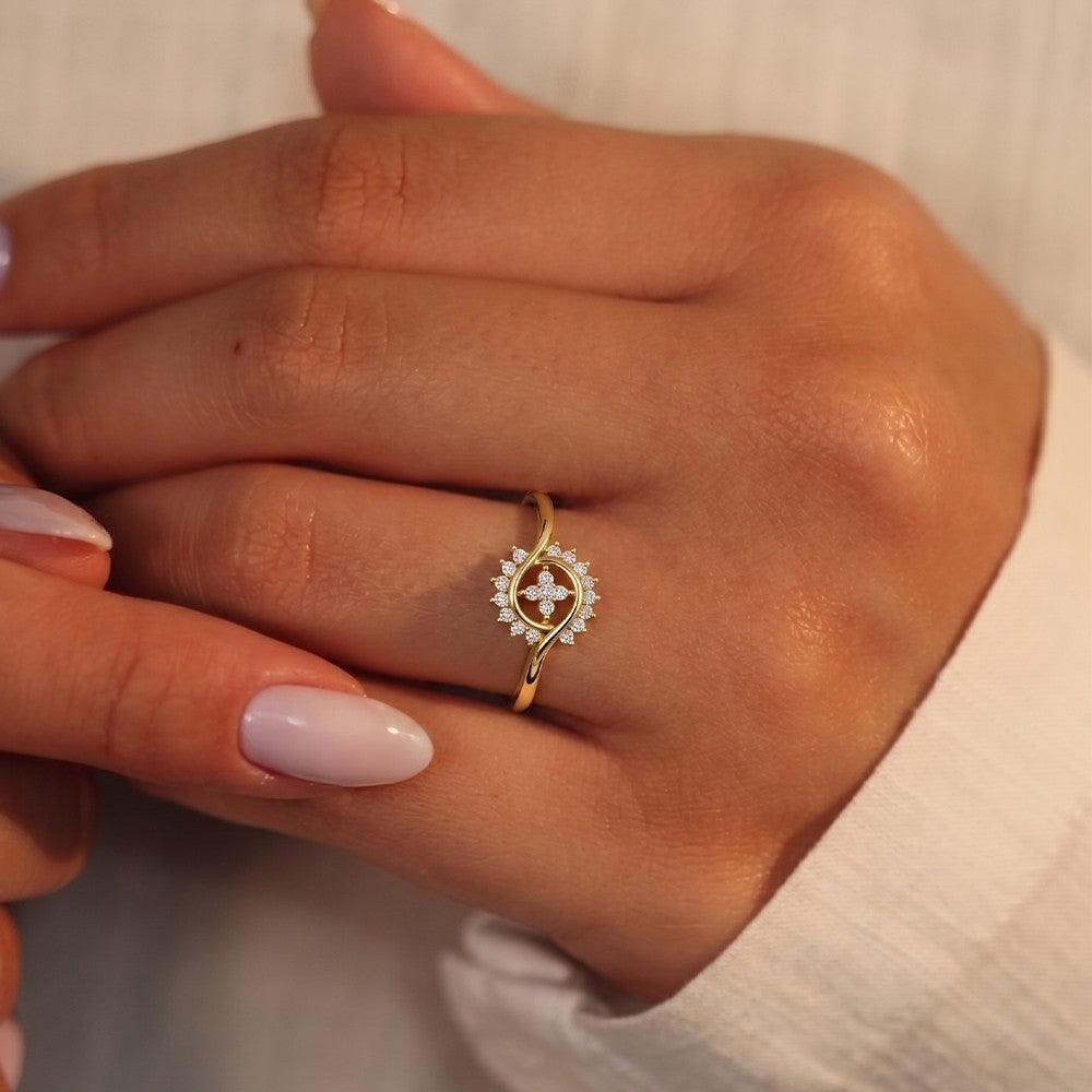 Gold ring with a diamond on a person's finger against a neutral background
