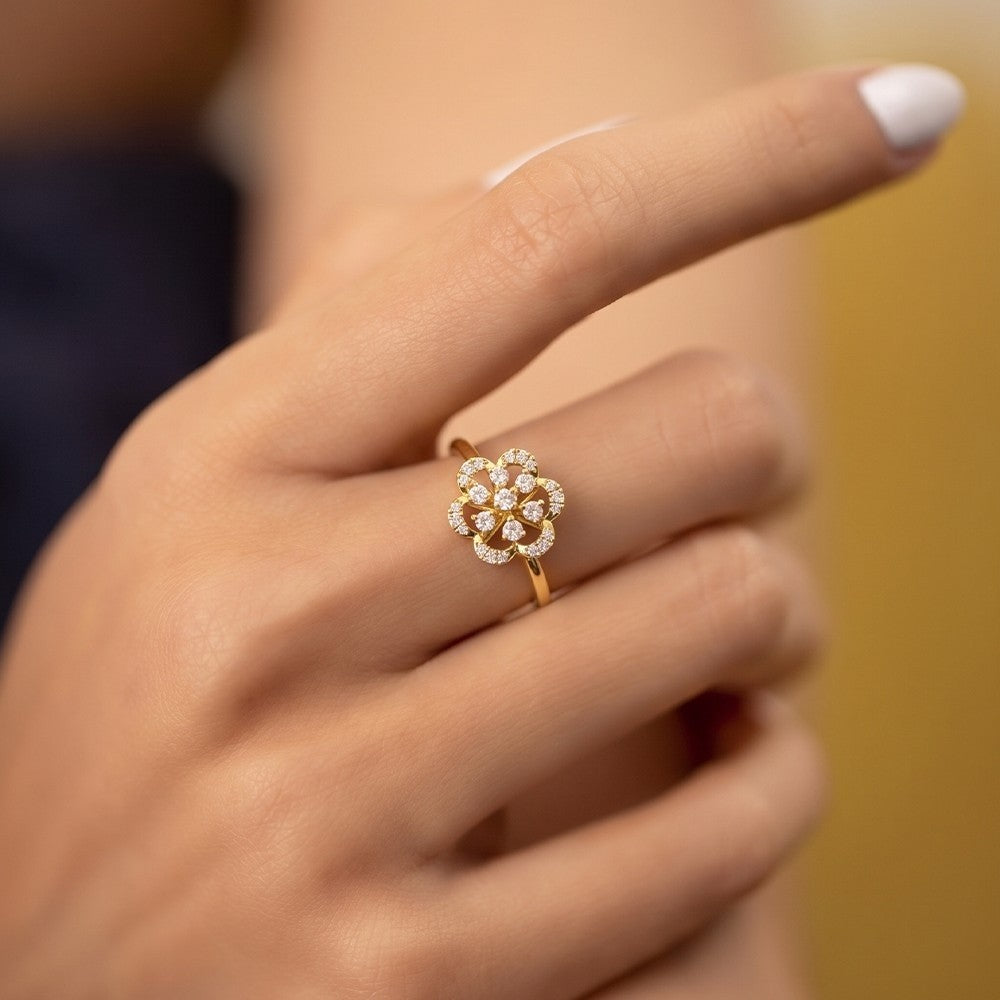 Close-up of a hand wearing a gold ring with a diamond floral design.