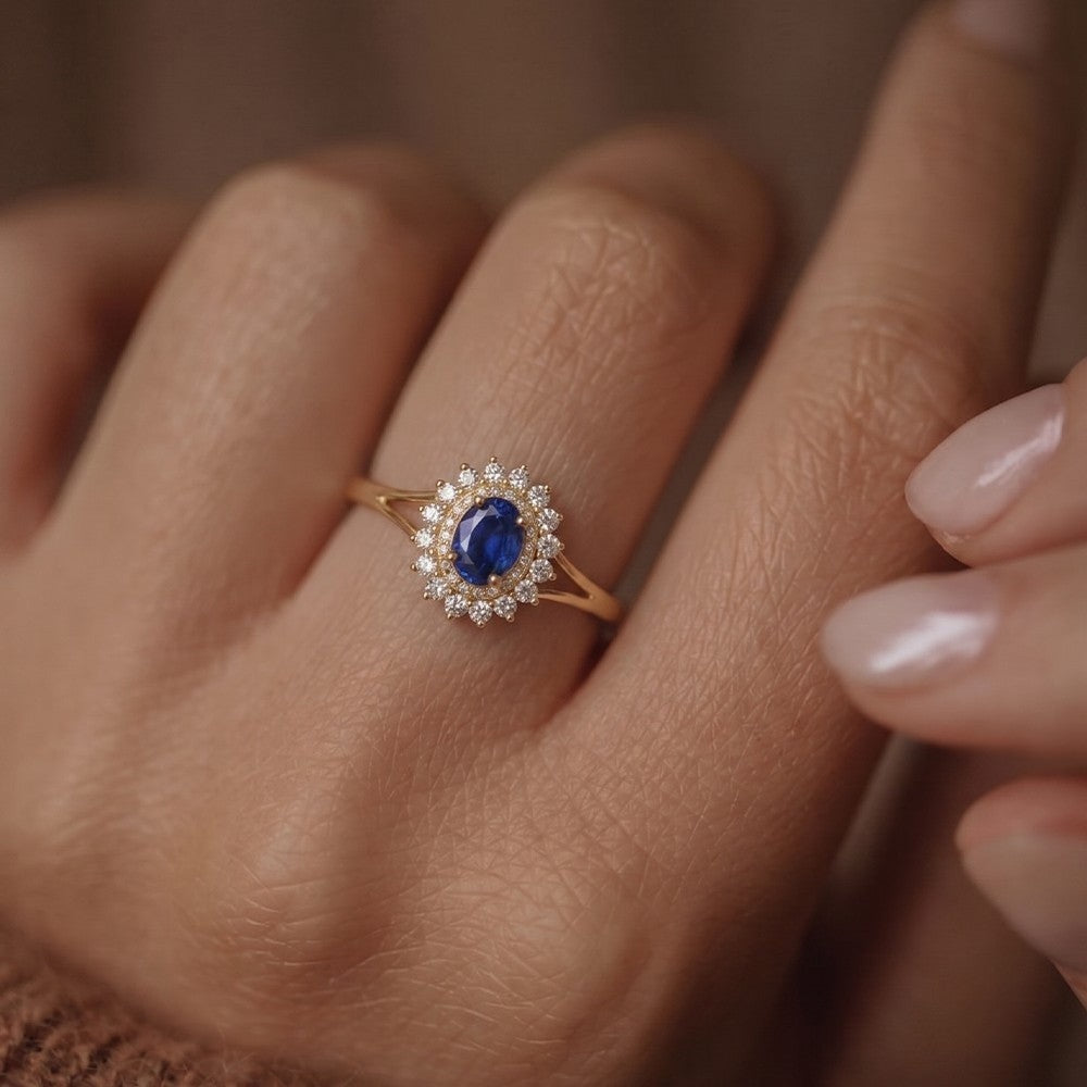 Gold ring with a blue gemstone and diamond halo on a hand