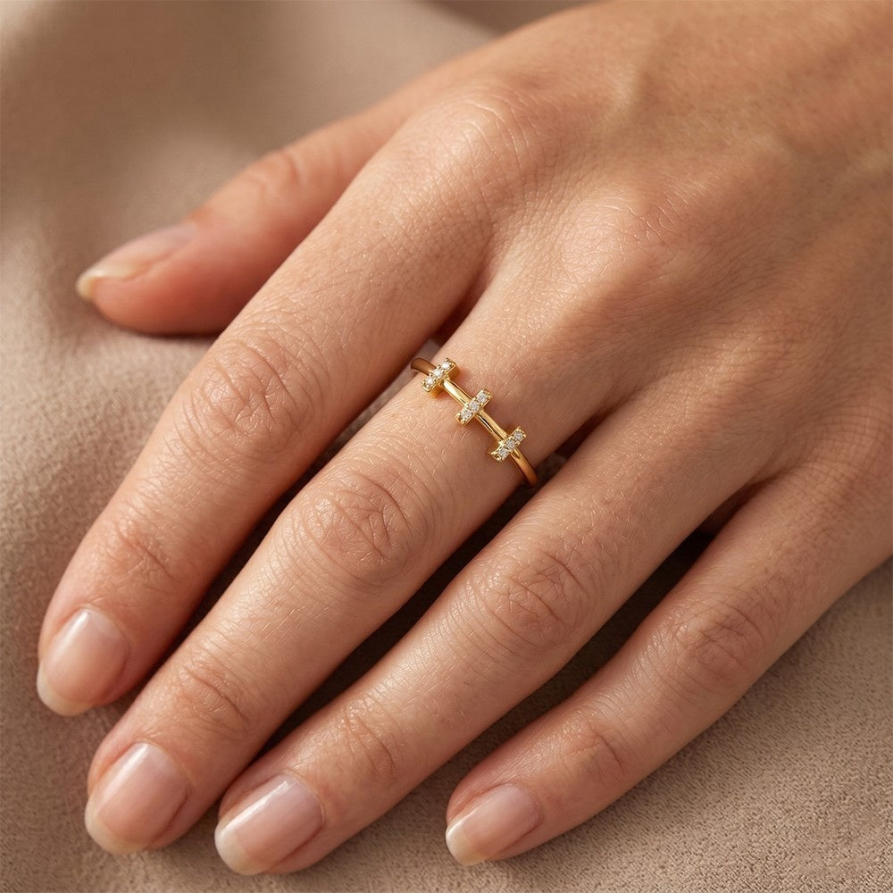 Gold ring with small diamonds on a hand against a beige background