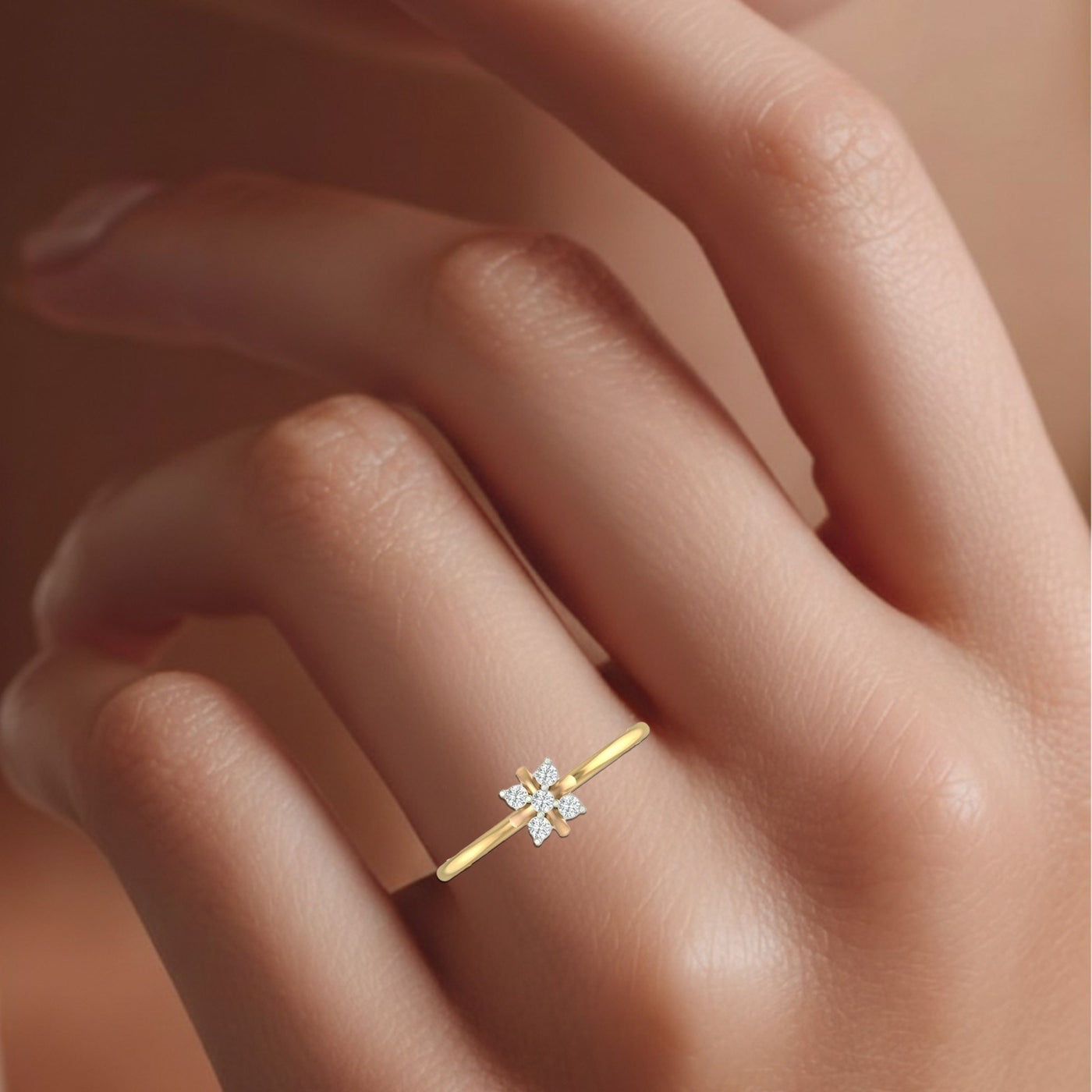 Gold ring with a diamond on a person's finger against a neutral background