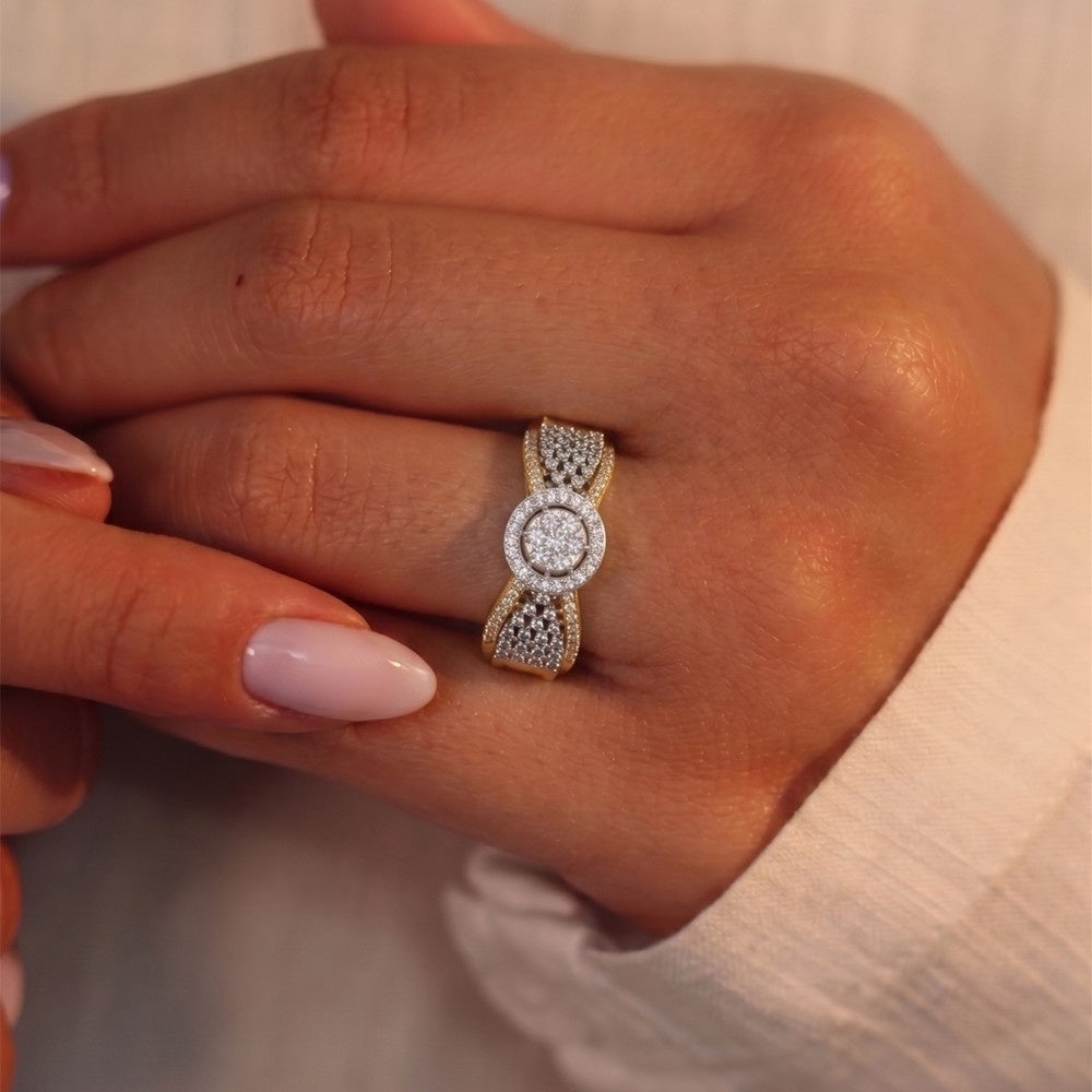Close-up of a hand wearing a gold and diamond ring against a neutral background