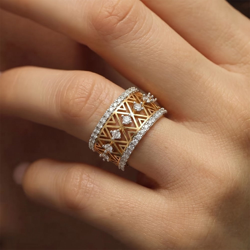 A close-up of a hand wearing a wide geometric ring in gold and diamond.
