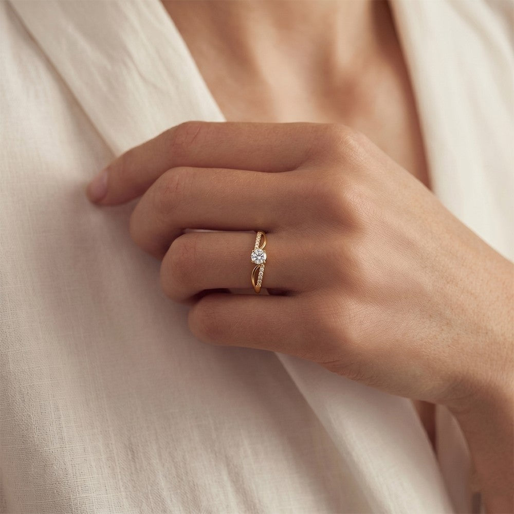 Hand wearing a gold ring with a diamond on a soft beige fabric background
