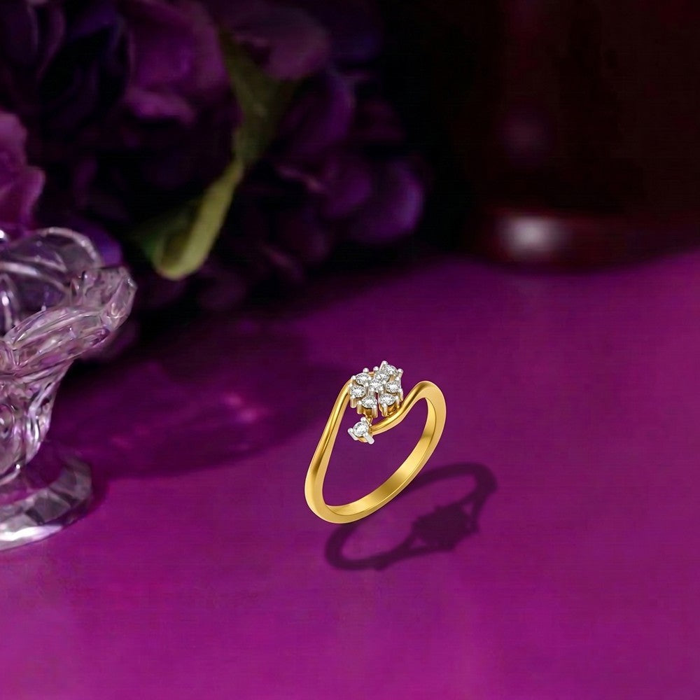 Gold ring with a diamond on a purple surface with flowers in the background.