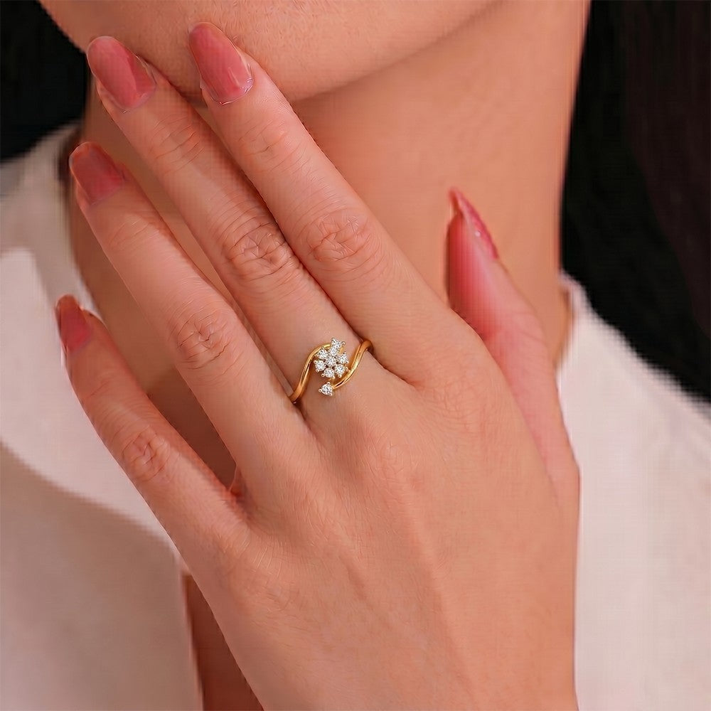 Hand wearing a gold ring with a diamond cluster, against a neutral background