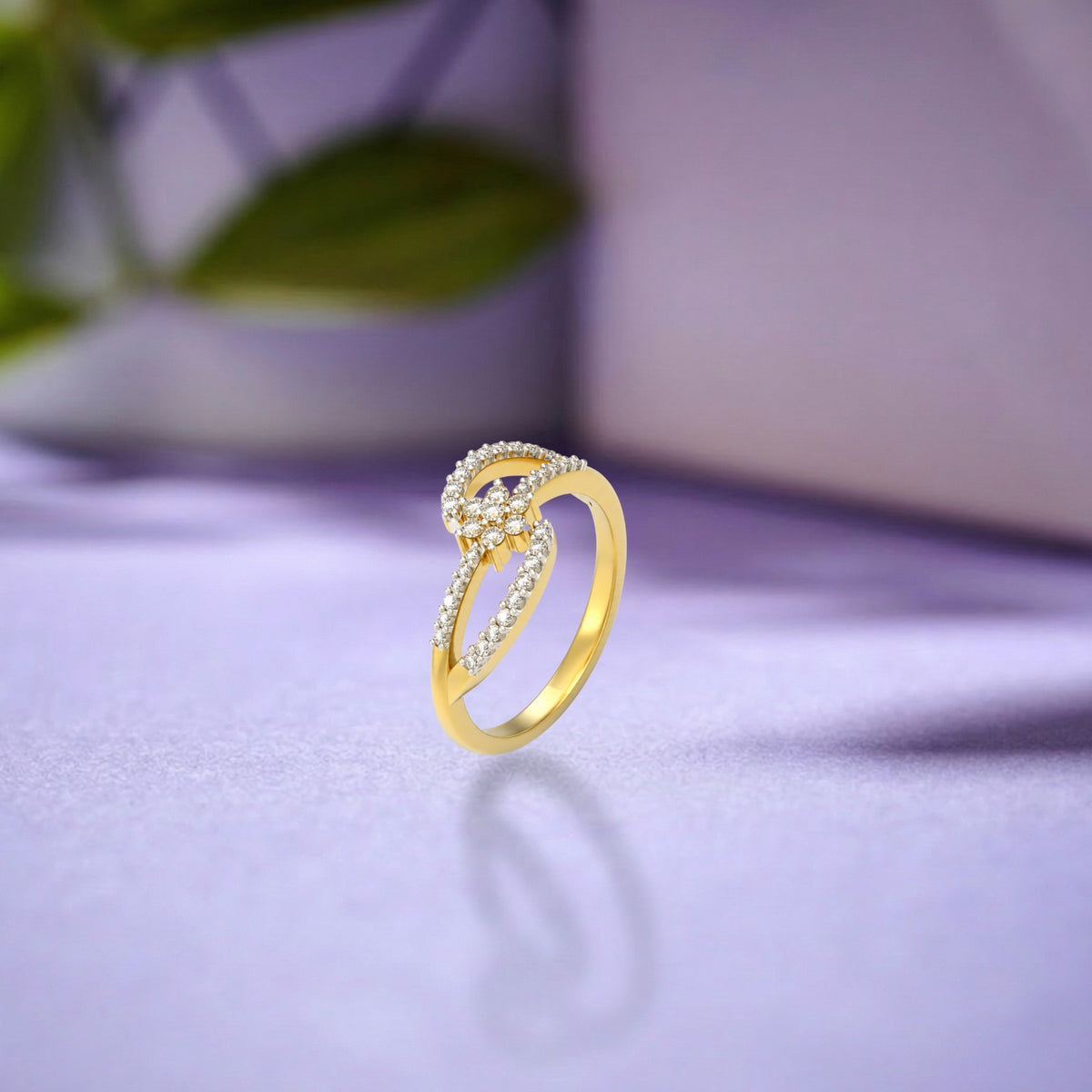 A gold and diamond ring with floral design, resting on a light purple reflective surface with a soft-focus background.