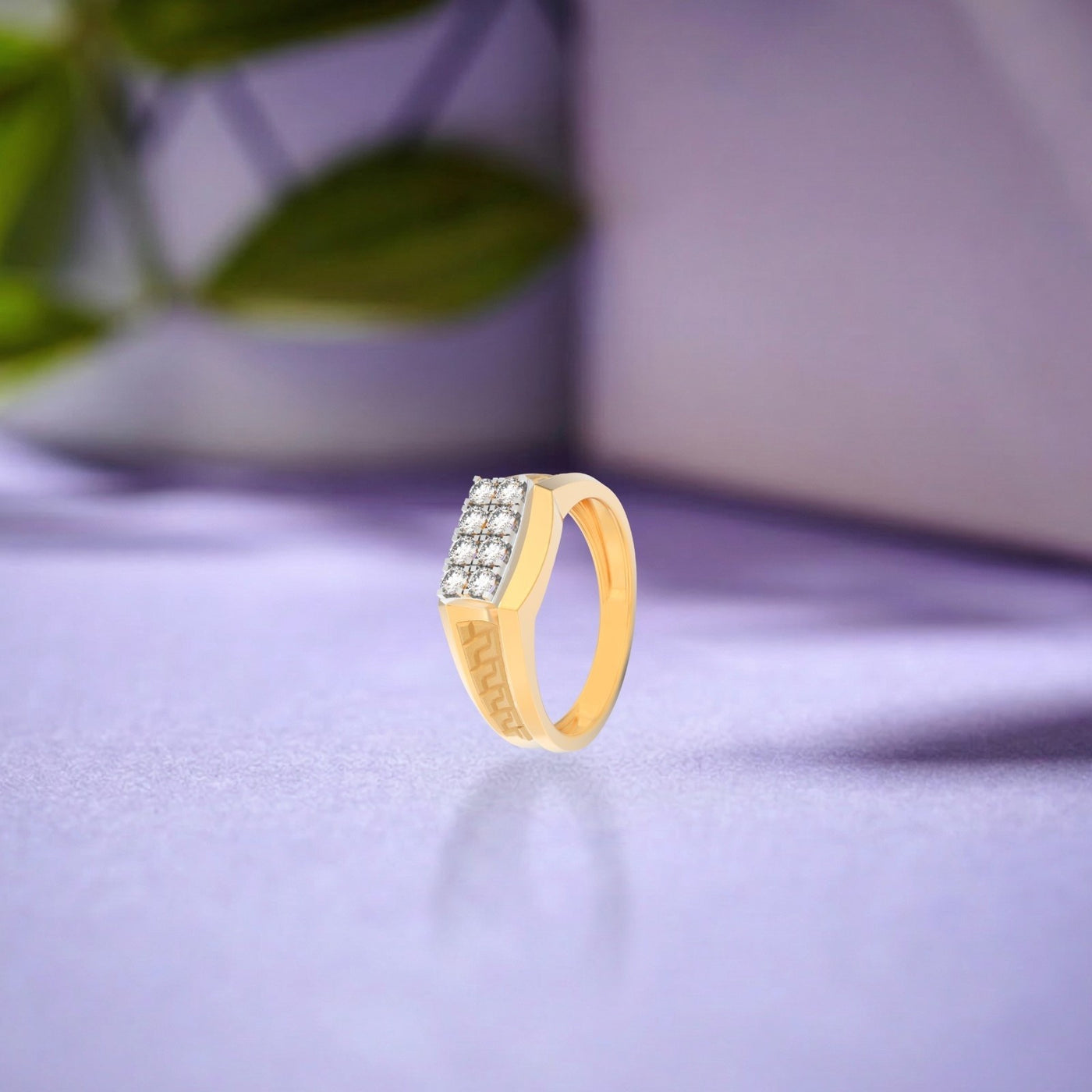 Gold ring with embedded stones on a light purple surface
