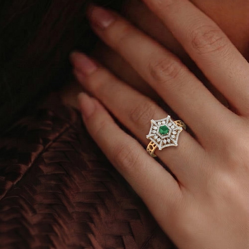 Close-up of a hand wearing a decorative ring with a emerald gemstone on a textured brown surface.