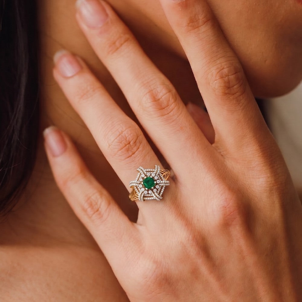 Close-up of a hand wearing a gold ring with a green gemstone.