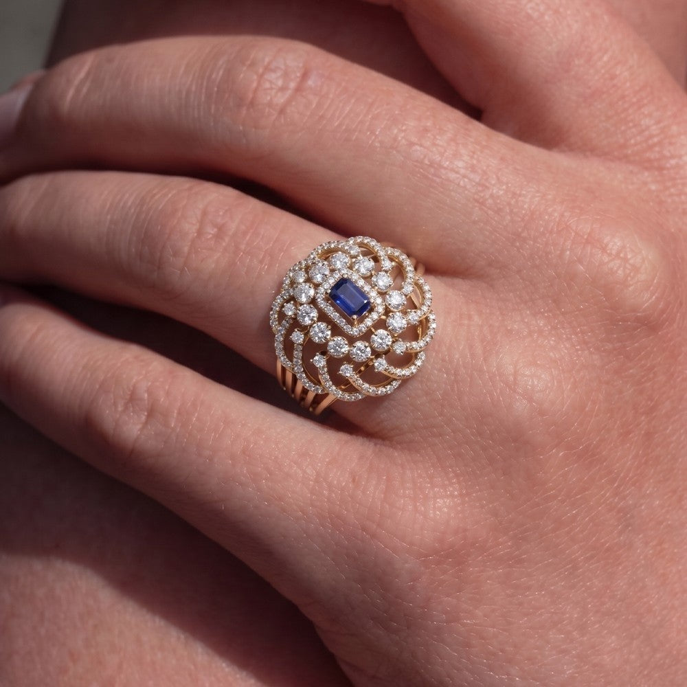 Close-up of a hand wearing an ring with a blue gemstone and diamond accents.