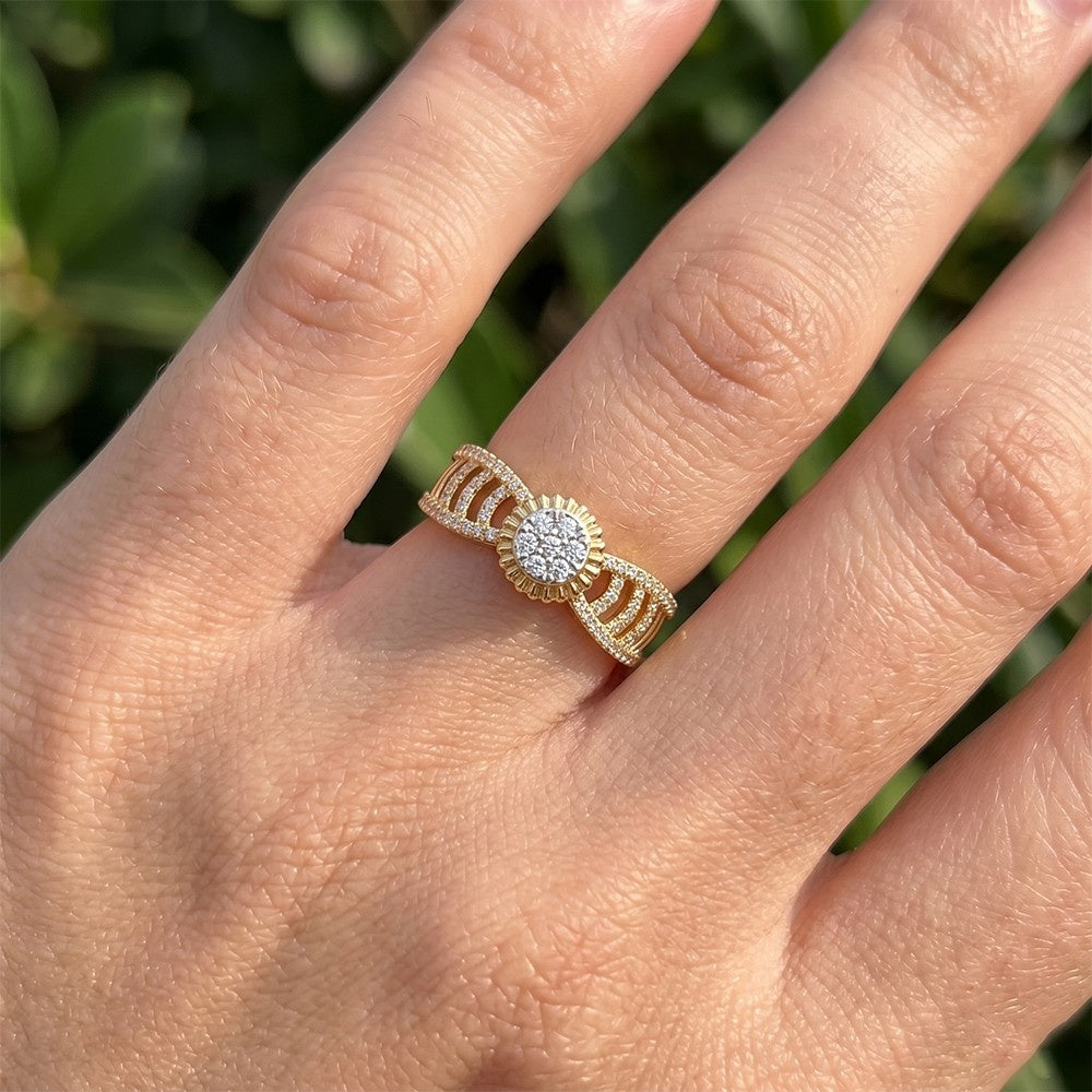 Gold ring with a diamond on a person's finger against a blurred green background