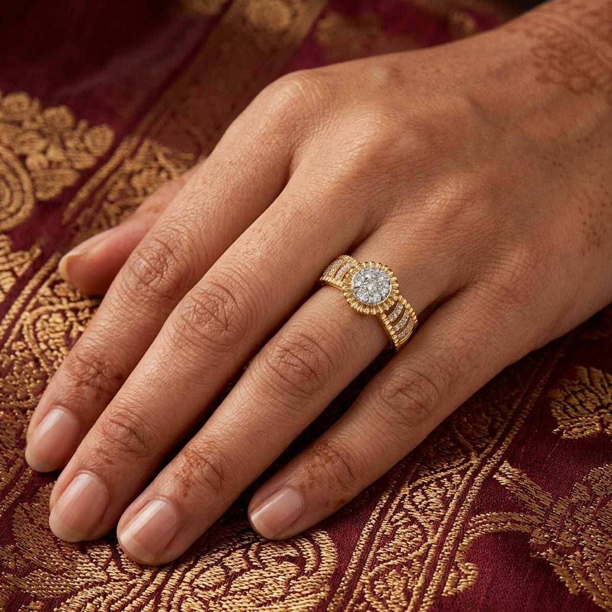 Gold ring with a diamond on a person's finger against a red saree background