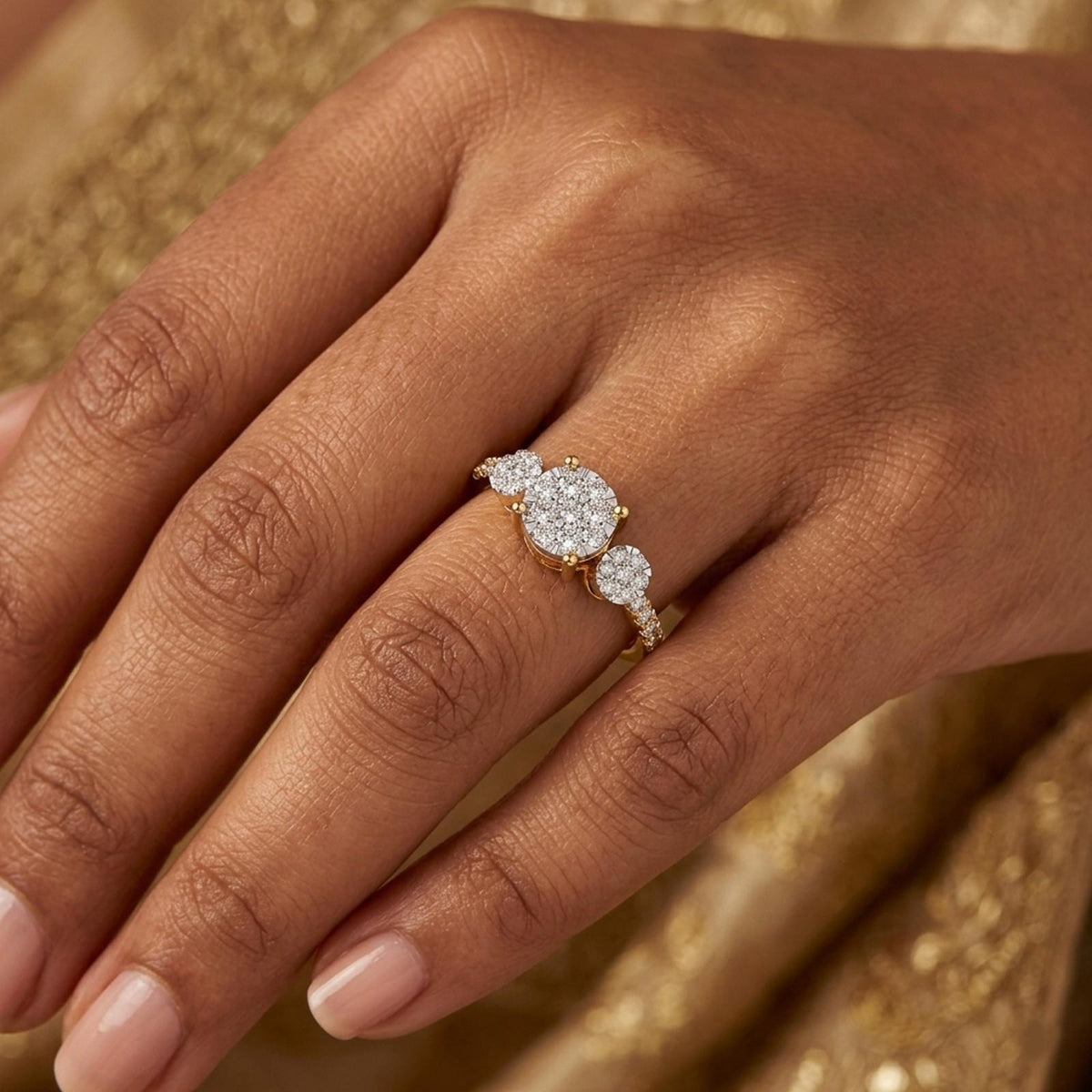 A close-up of a hand wearing a gold ring diamond center, set against a saree.
