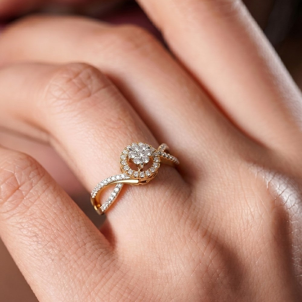 A close-up of a gold ring with a round-cut diamond center stone and a curved pavé band, worn on a hand.