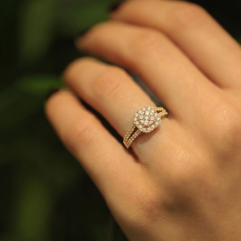 Rose gold ring with diamonds on a hand against a blurred green background