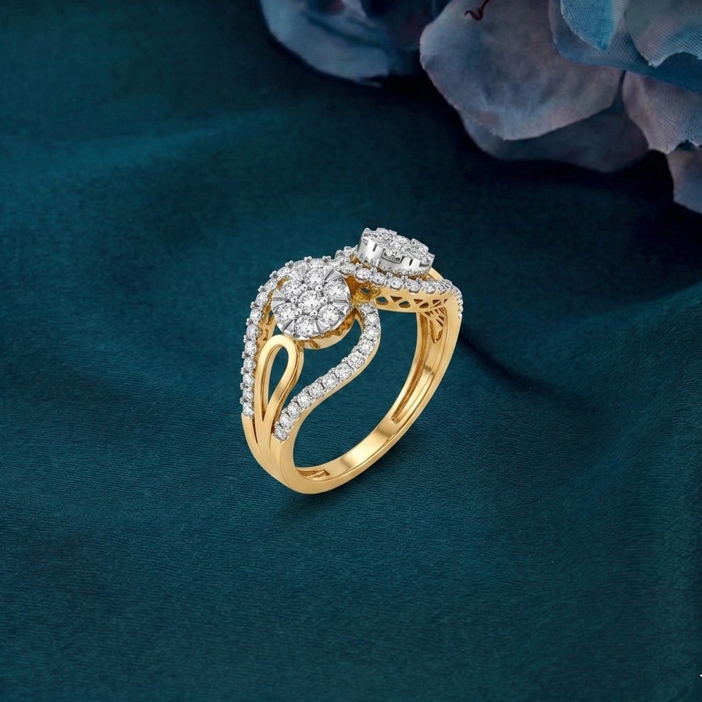 A yellow gold ring with a round cluster design, resting on a dark teal fabric background.