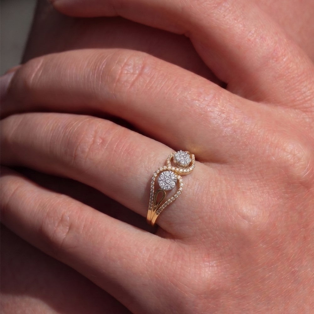 Rose gold ring with diamonds on a person's finger.