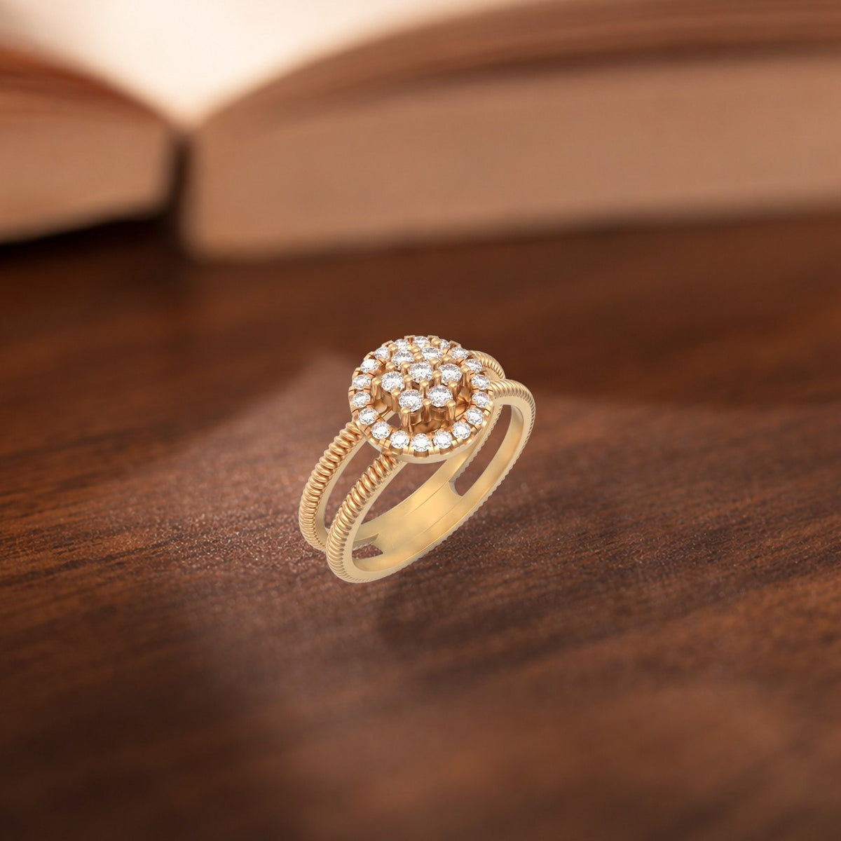 A gold ring with a round cluster of clear stones on a textured band, resting on a dark wooden surface with a blurred book in the background.