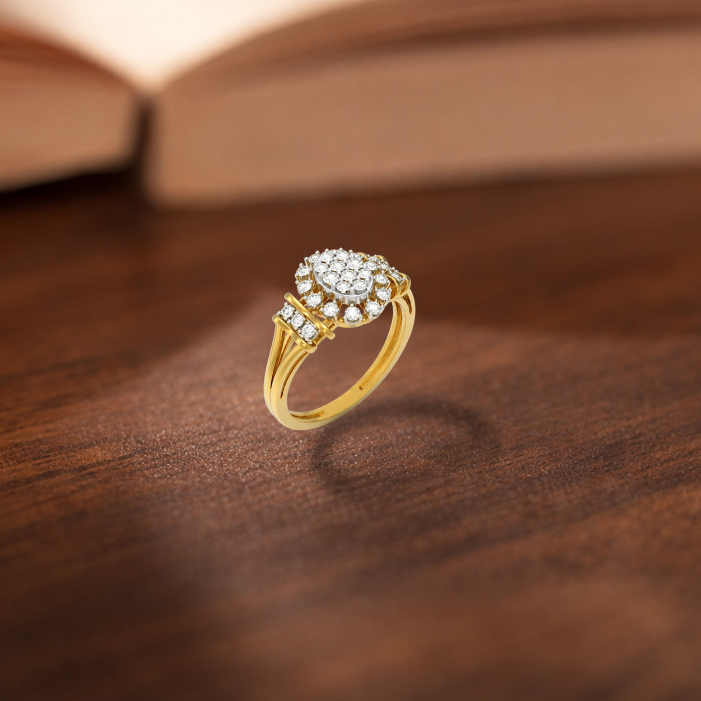 A gold ring with a round cluster of, resting on a dark wooden surface with a blurred book in the background.