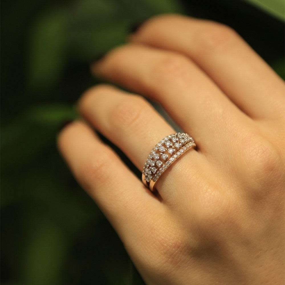 A close-up of a hand wearing a gold ring, blurred dark green background.