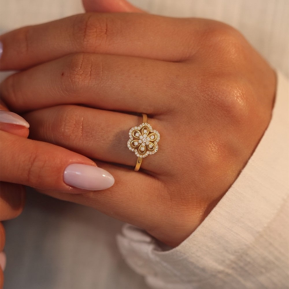 Close-up of a hand wearing a gold ring on a neutral background.