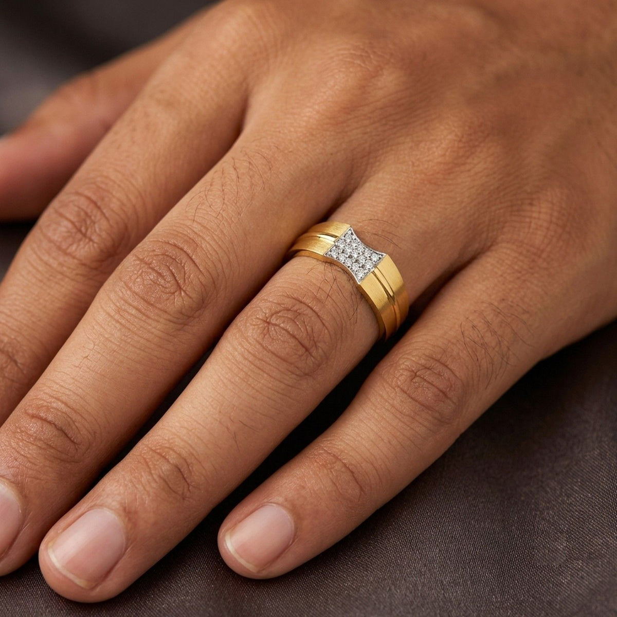 Hand wearing a gold ring with geometric design on a wooden surface.