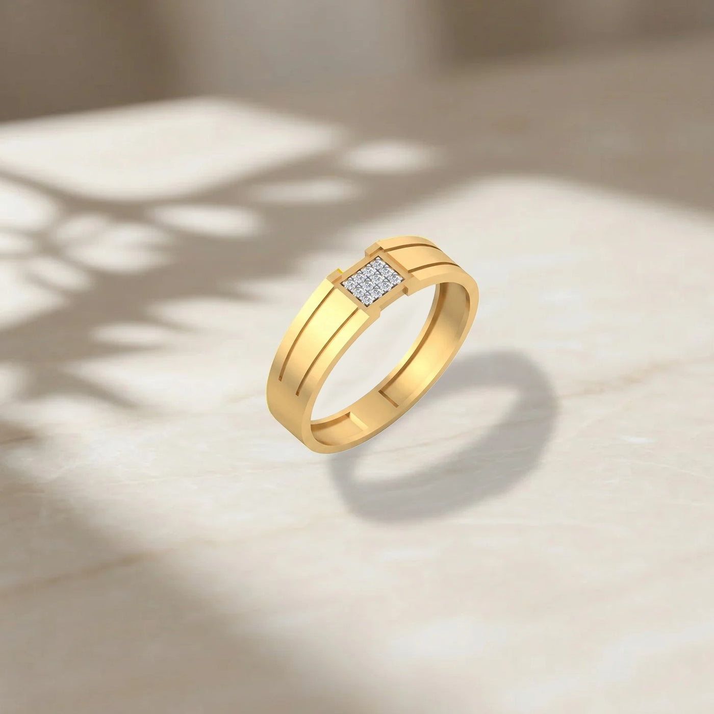A gold ring with a rectangular pavé diamond center stone, displayed on a light marble surface with soft shadows.