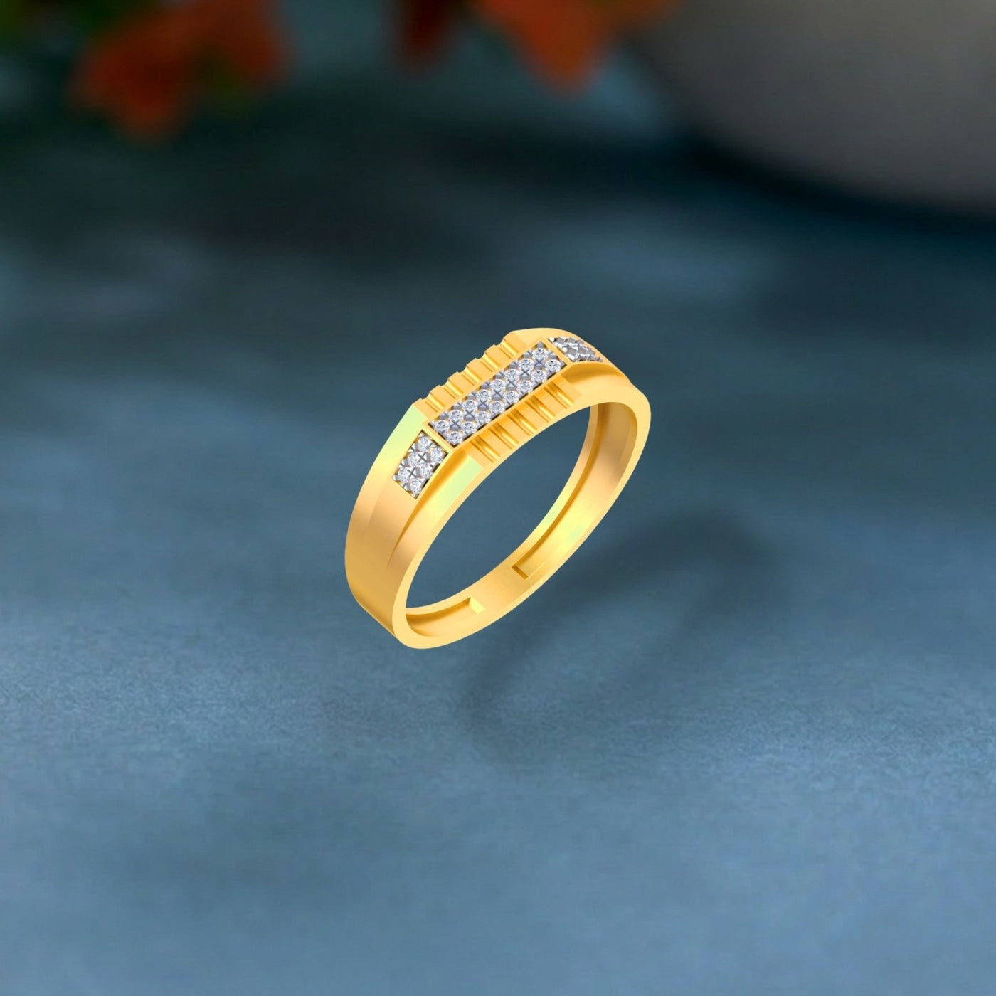 Gold ring with a textured channel-set diamond band, shown on a teal surface.