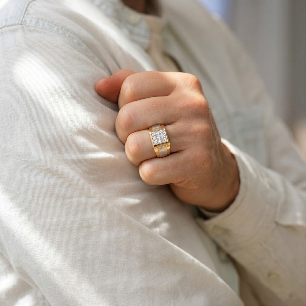 Hand wearing a gold ring with a diamond, holding onto a white shirt.
