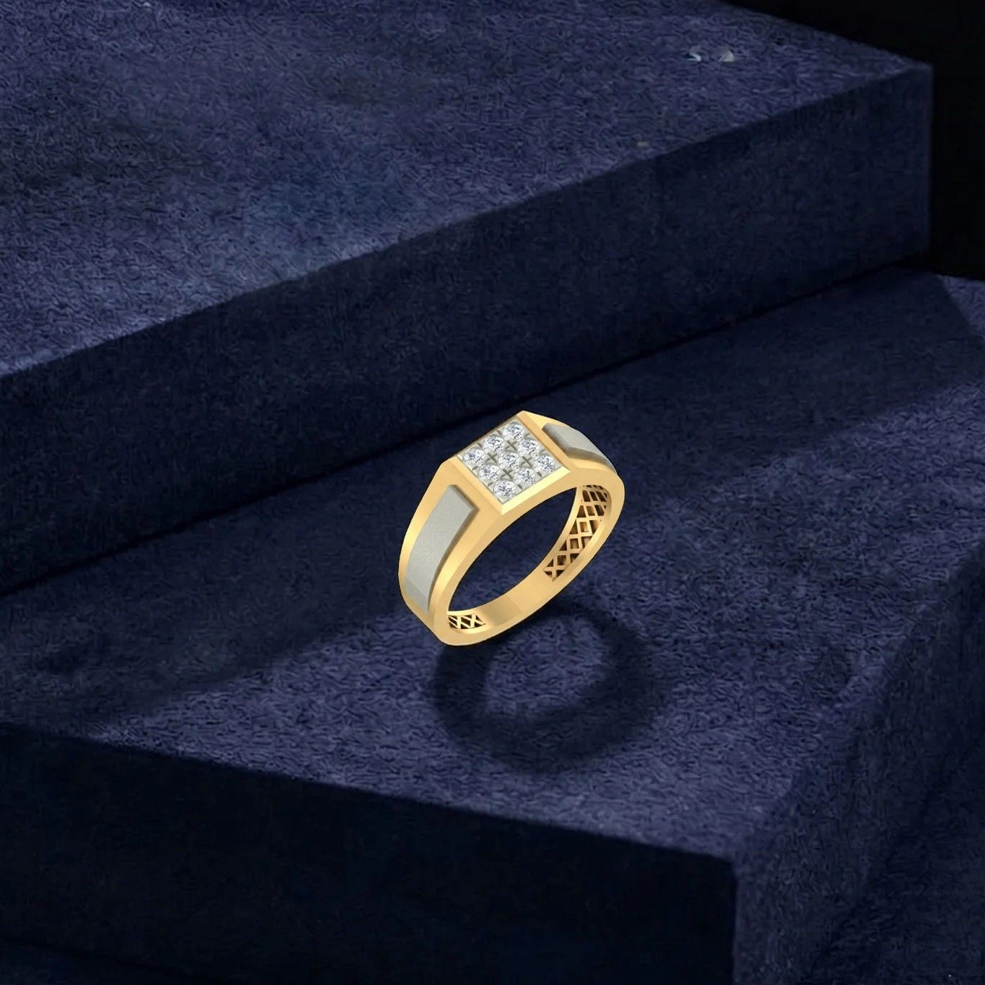 A gold signet-style ring with a rectangular and a white inlay, displayed on a dark textured pedestal.