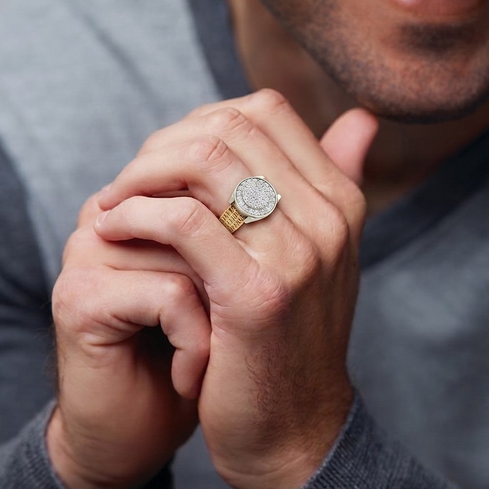 Close-up of a hand wearing a gold and diamond ring, with a blurred gray background
