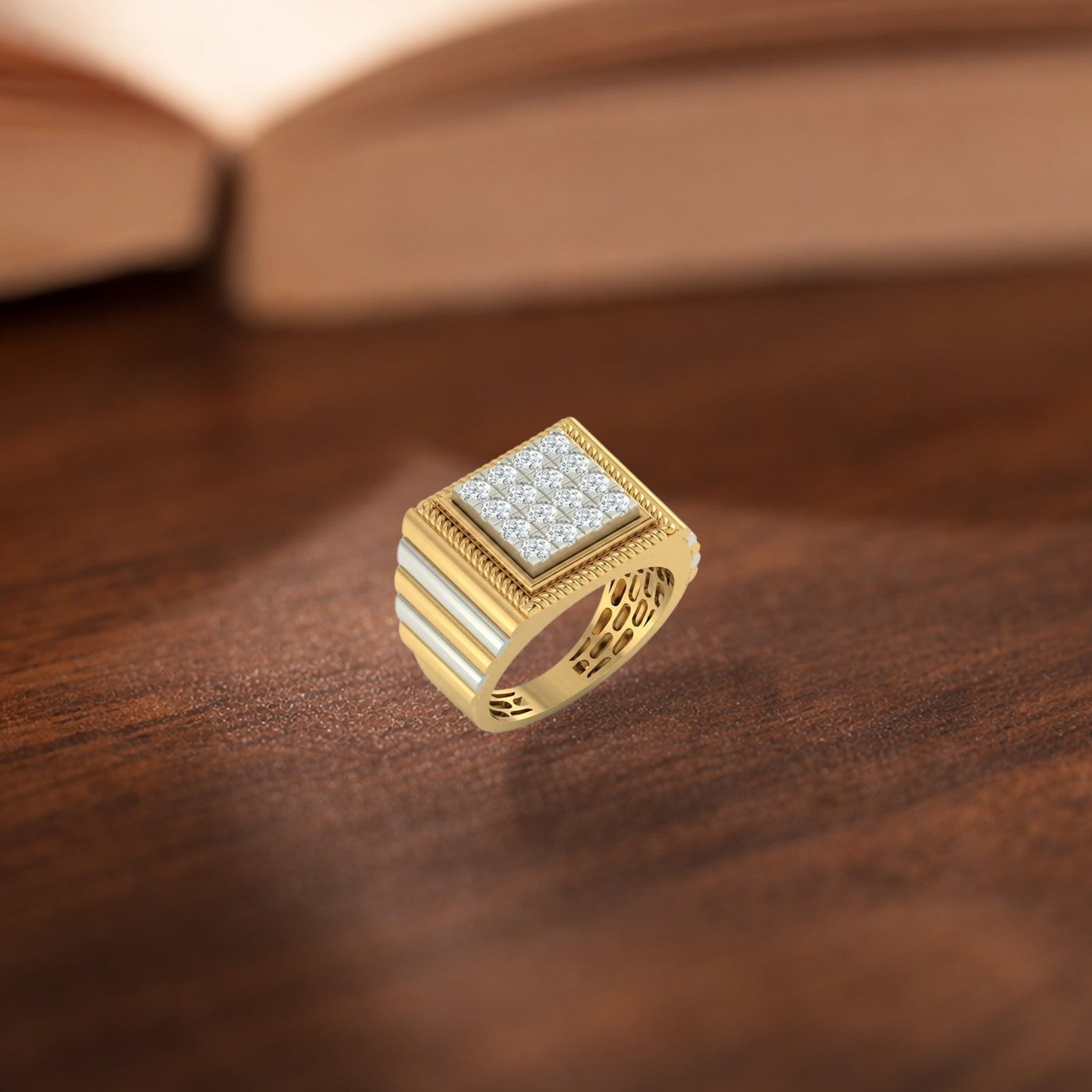 A gold signet-style ring with a square face set, resting on a dark wooden surface with a blurred book in the background.