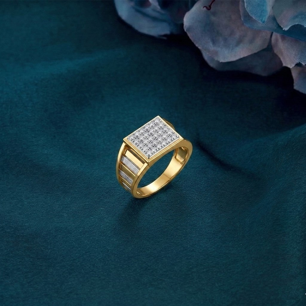 A gold and diamond ring with a square design, displayed on a dark teal fabric background with blurred blue flowers in the corner.