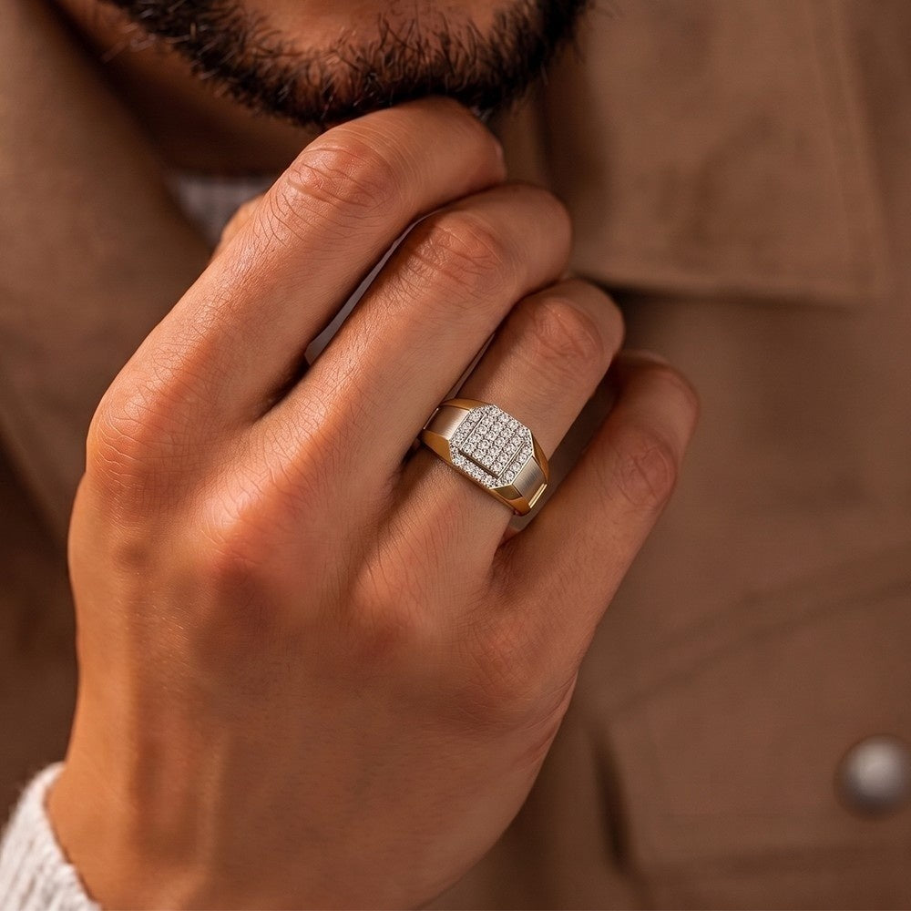 Hand wearing a gold ring with diamonds against a brown background