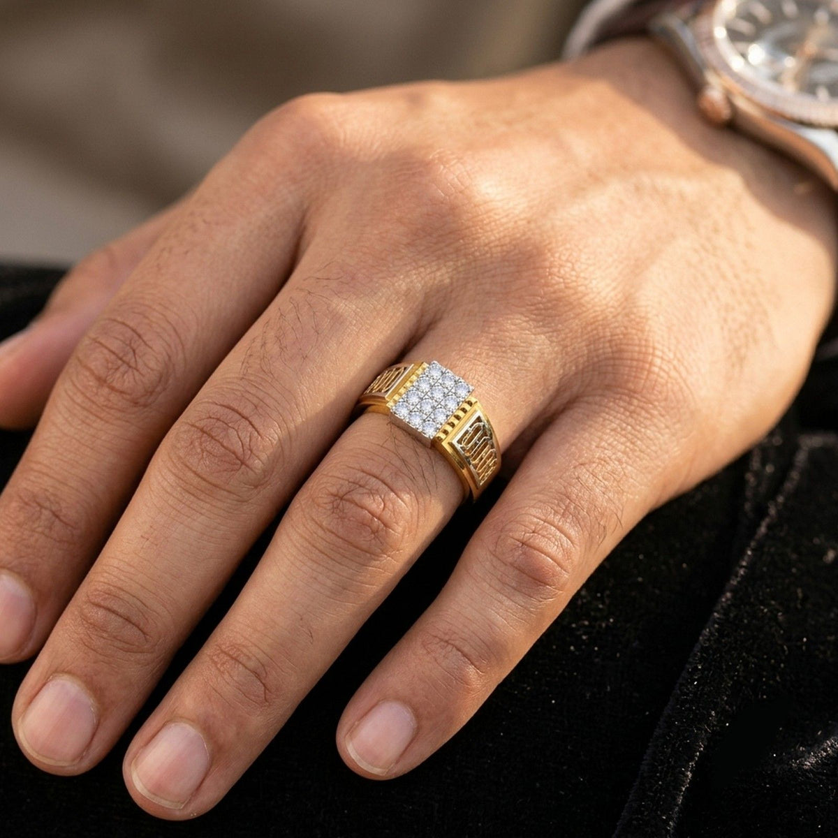 A close-up of a man's hand wearing a gold ring with a square pavé diamond center.