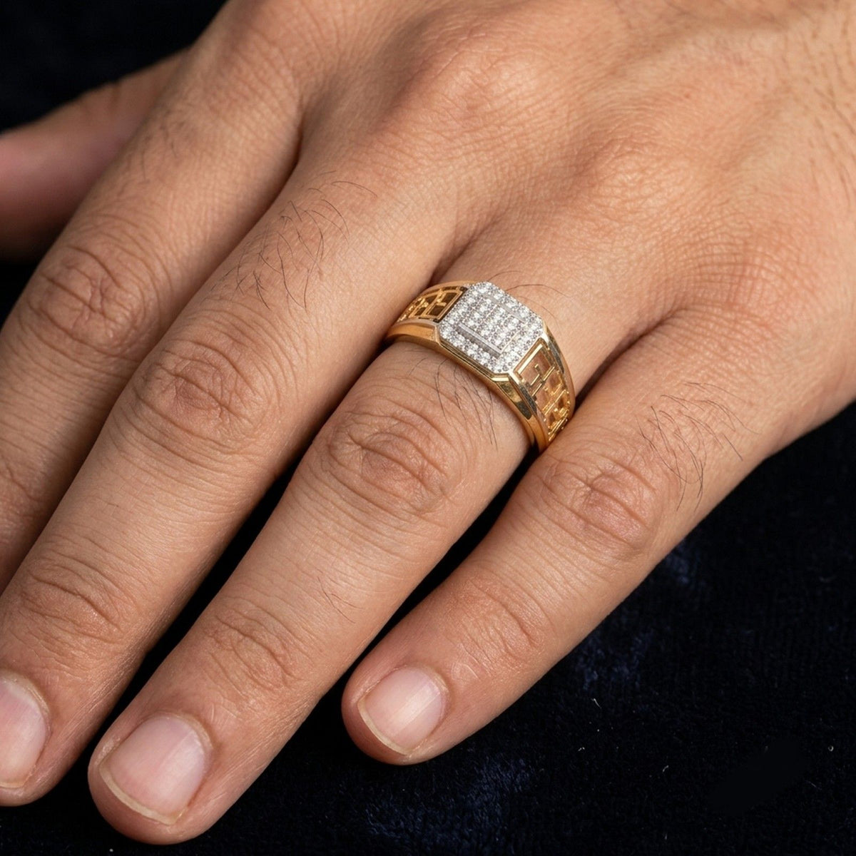 A gold ring with a square diamond-encrusted worn on a person's finger.