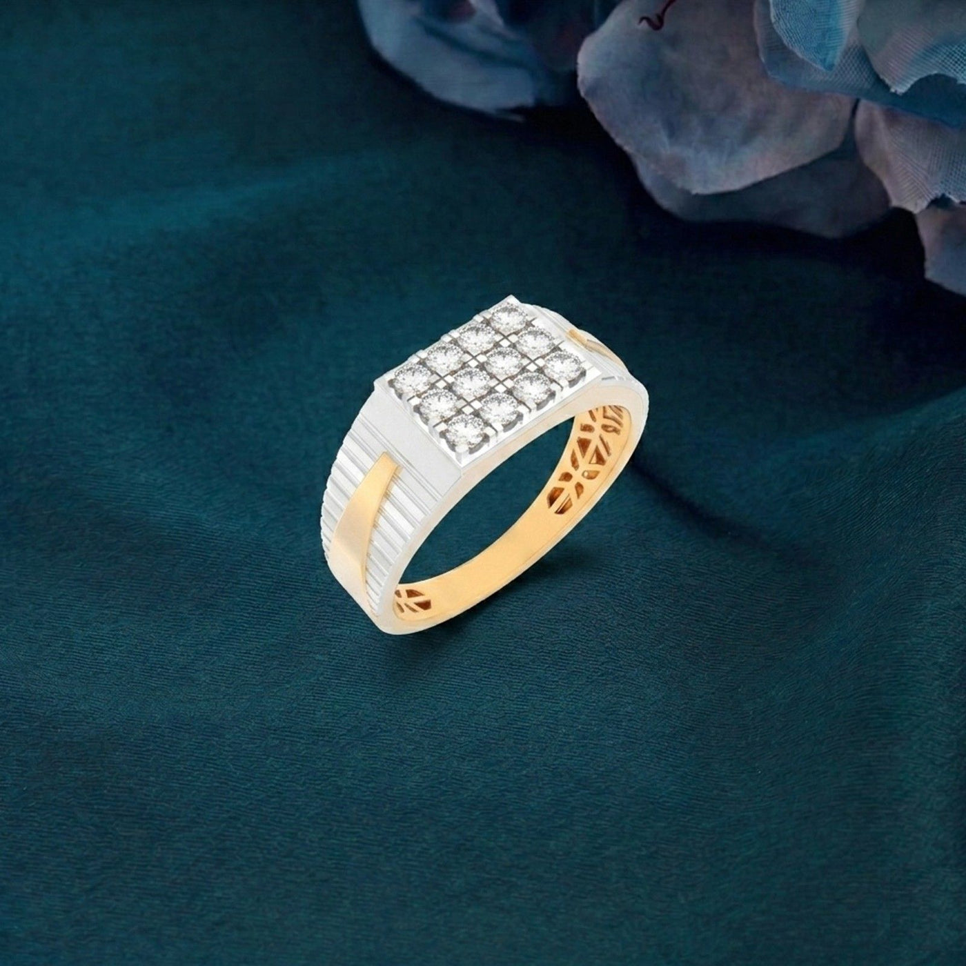 Gold and white ring with diamond accents on a dark green fabric background.