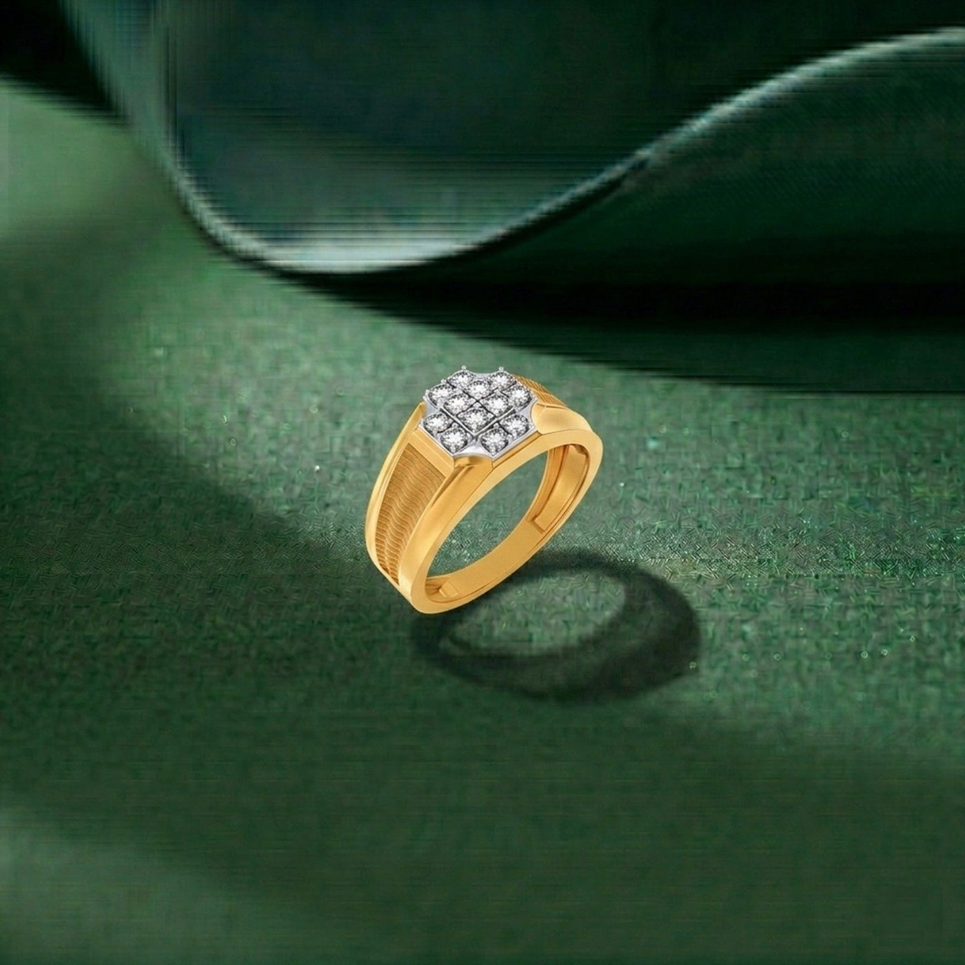 A gold ring with a round cluster, resting on a dark green textured surface with a dark green satin fabric in the background.